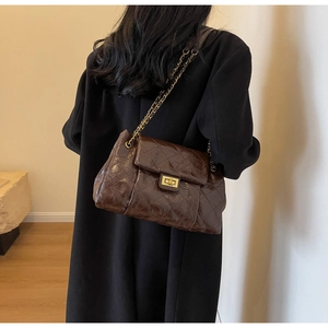 Close-up of brown quilted oil wax leather bag with gold chain strap and metal turn-lock