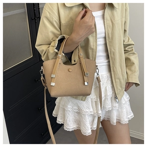 Detail of khaki woven texture bucket bag styled with casual outfit in indoor setting