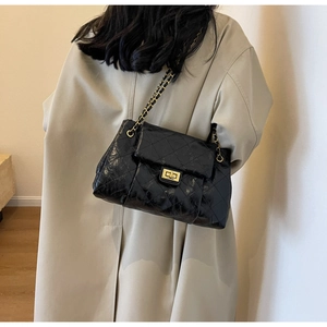 Detail view of black quilted leather shoulder bag with golden chain and twist lock