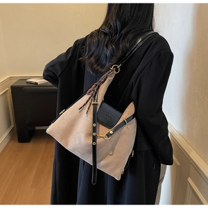 Detail of light brown suede tote bag with black leather strap and golden hardware