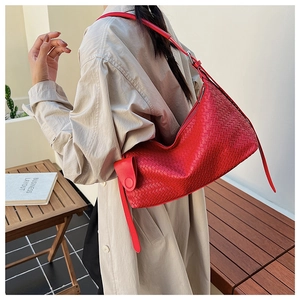 Detail of red woven leather tote bag shown from side view on model with casual style