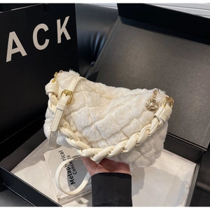 Détail du sac bandoulière en peluche crème avec anse tissée et breloque dorée ronde