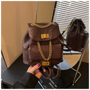 Detail eines dunkelbraunen Lederrucksacks mit goldenen Ketten und Metallverschlüssen