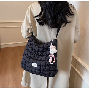 Close-up of black quilted puffer tote bag featuring brand logo and cute rabbit charm