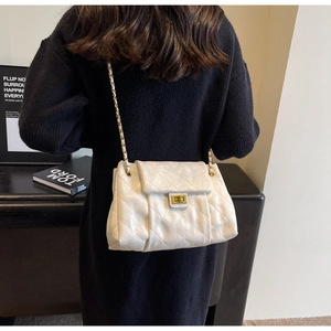 Detail of white quilted leather crossbody bag with gold chain strap and metal clasp