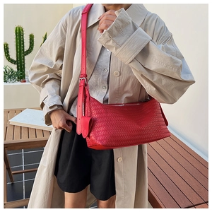Detailed close-up of large red woven leather hobo bag with wide adjustable shoulder strap