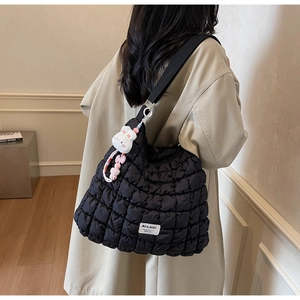 Close-up of black quilted puffer tote bag with MULAIDI label and cute white rabbit charm