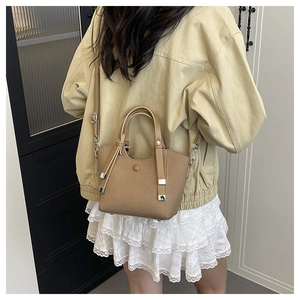 Detail of khaki woven bucket bag with silver hardware and adjustable shoulder strap