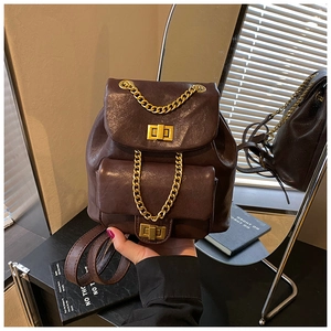 Detailansicht eines dunkelbraunen Lederrucksacks mit doppelten Goldverschlüssen und Ketten