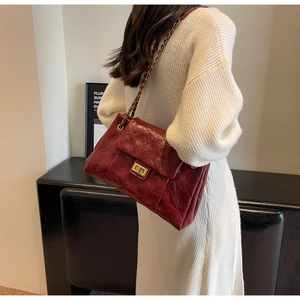 Detail of burgundy quilted leather handbag with gold chain strap and twist lock closure