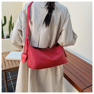 Detailed view of red woven hobo bag with adjustable strap and heart-shaped charm accessory