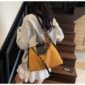 Detail of vintage suede tote bag with leather straps on a wooden staircase model view