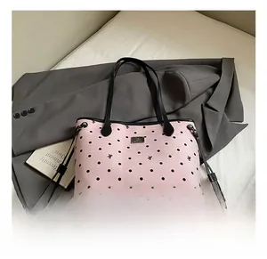 Detailed view of pink polka dot tote bag with metal logo on a grey suit background