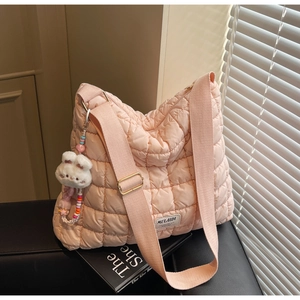 Detail of pink quilted nylon puffer tote bag with adjustable strap and cute rabbit charm
