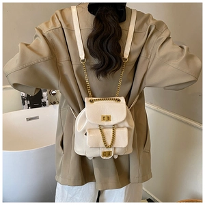 Detail eines cremefarbenen Kunstleder-Minirucksacks mit Goldkette und Drehverschluss