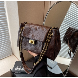 Detail of coffee brown quilted chain bag with gold twist lock in natural light