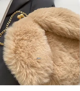 Gros plan d'un sac à main en peluche beige avec fermoir boule doré et bandoulière chaîne
