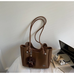 Dettaglio della borsa a mano marrone in pelle martellata con hardware argento e pendente