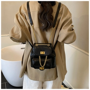Schwarzer Lederrucksack mit Goldkettenriemen und Drehverschluss am Rücken eines Models