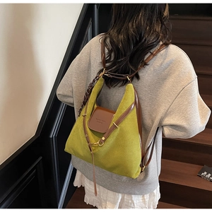 Detail of green suede backpack with leather trim and metallic buckle shown on a model