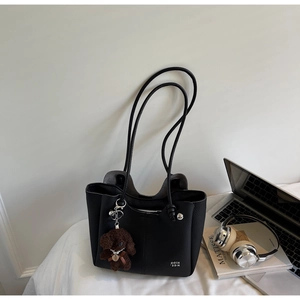 Dettaglio della borsa tote nera in pelle martellata con bordo a onde e ciondolo