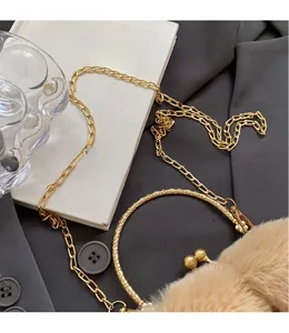 Détail du sac en fausse fourrure beige avec poignée en métal gravé et chaîne dorée