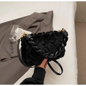 Détails d'un sac à main noir en peluche matelassé avec poignée tressée et finitions dorées