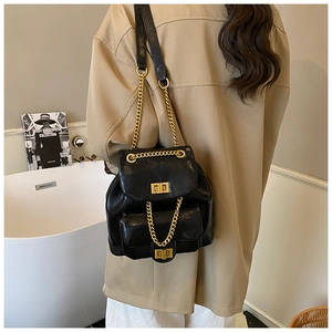 Detail eines glänzenden schwarzen Lederrucksacks mit Doppelklappe und Goldkettenriemen