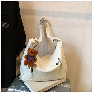 White faux leather crescent bag with wide strap and cute bear charm in daily setting