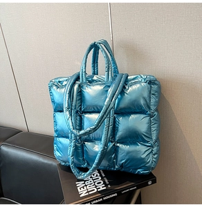 Close-up of metallic blue quilted tote bag showing padded texture and strap details
