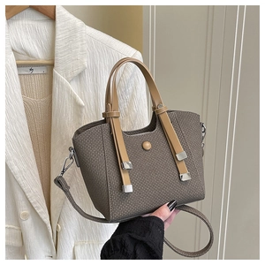 Detail of brown woven fabric bucket bag with leather handles and silver hardware close-up