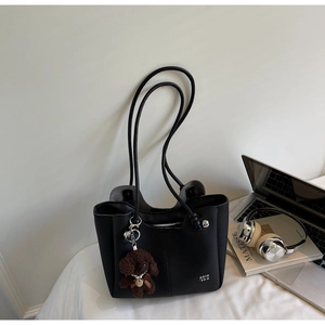 Dettaglio borsa tote nera in pelle martellata con un simpatico ciondolo a cucciolo