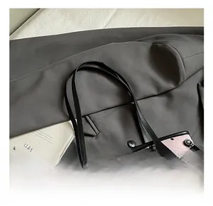 Detail of pink polka dot tote bag with black leather handles and metal rivets