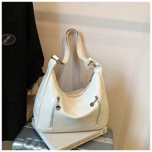 Detail view of cream white Hobo bag with dual silver decorative zippers on a silver suitcase