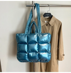 Detail of blue puffer tote bag featuring quilted metallic texture and square patterns