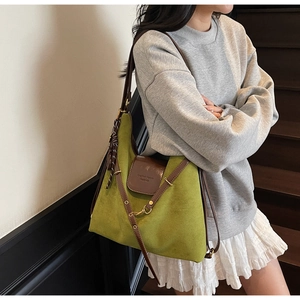 Green suede tote bag with brown leather straps shown on a model in a lifestyle setting
