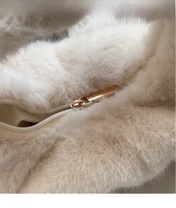 Détail de la fermeture éclair dorée et du tissu pelucheux beige doux du sac à main chic
