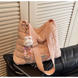 Detail view of pink quilted tote bag with plush bunny charm and beaded strap accents