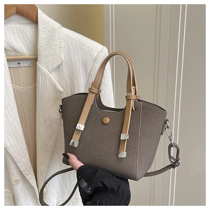 Detail of a brown woven bucket bag with smooth leather straps and silver metal buckles