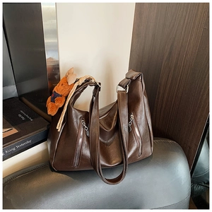 Detail showing deep brown faux leather tote with metal zippers and cute bear charm