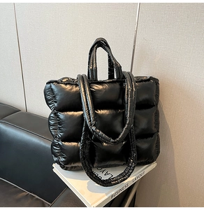 Detail of glossy black quilted puffer tote bag with nylon texture and shoulder strap