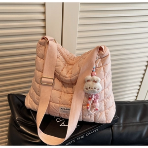 Detail of pink quilted puffer tote bag with plush bunny charm and beaded accessory