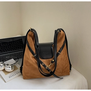 Detail of a brown suede tote bag with black leather flap and embossed branding text
