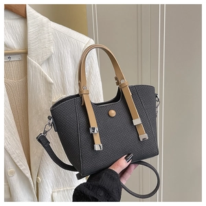 Detail of dark grey woven basket bag featuring tan leather straps and silver buckle detail