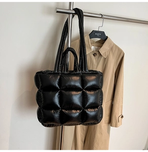 Macro detail of black quilted puffer tote bag showing glossy nylon fabric and padded texture
