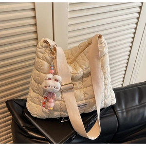 Detail view of the beige quilted puffer tote bag with a cute white rabbit plush charm