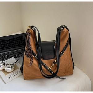 Detailed view of brown suede tote bag with black leather flap and braided pendant detail