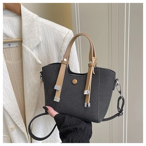 Detail of black woven texture handbag with brown handles in an elegant office setting