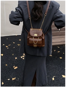 Detail eines braunen Vintage-Lederrucksacks mit goldenen Ketten und Drehverschluss