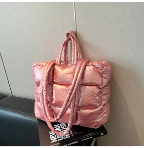 Close-up of metallic pink quilted tote bag with padded texture on a black leather bench